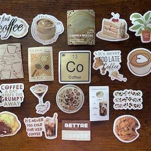 May include: A collection of coffee-themed stickers featuring various designs including cups of coffee, a slice of cake, a potted plant, a periodic table element labeled Co Coffee, and text phrases such as but first coffee, It's never TOO LATE For Coffee, and A COFFEE A DAY KEEPS THE GRUMPY AWAY.
