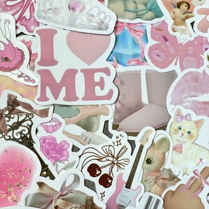 May include: A collection of pink and white stickers featuring various designs, including a crown, a heart with the text "I LOVE ME", a guitar, a cat, a flower, a pair of boots, and a cherub.