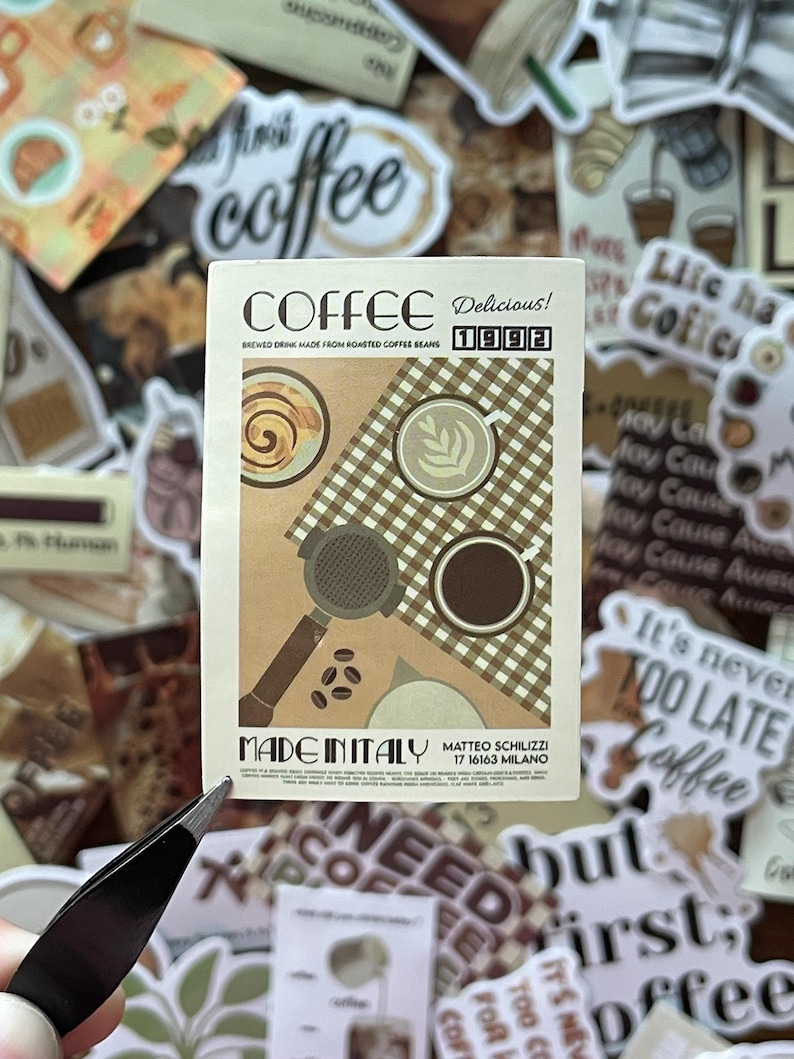 May include: A rectangular sticker featuring a tan and brown graphic of coffee items. Text reads COFFEE, Delicious! 1992, BREWED DRINK MADE FROM ROASTED COFFEE BEANS, MADE IN ITALY, and MATTEO SCHILIZZI 17 16163 MILANO. It shows a portafilter, coffee beans, and cups.