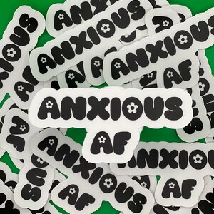 May include: A collection of white stickers with black text and a small flower design. The text on the stickers reads "Anxious AF".