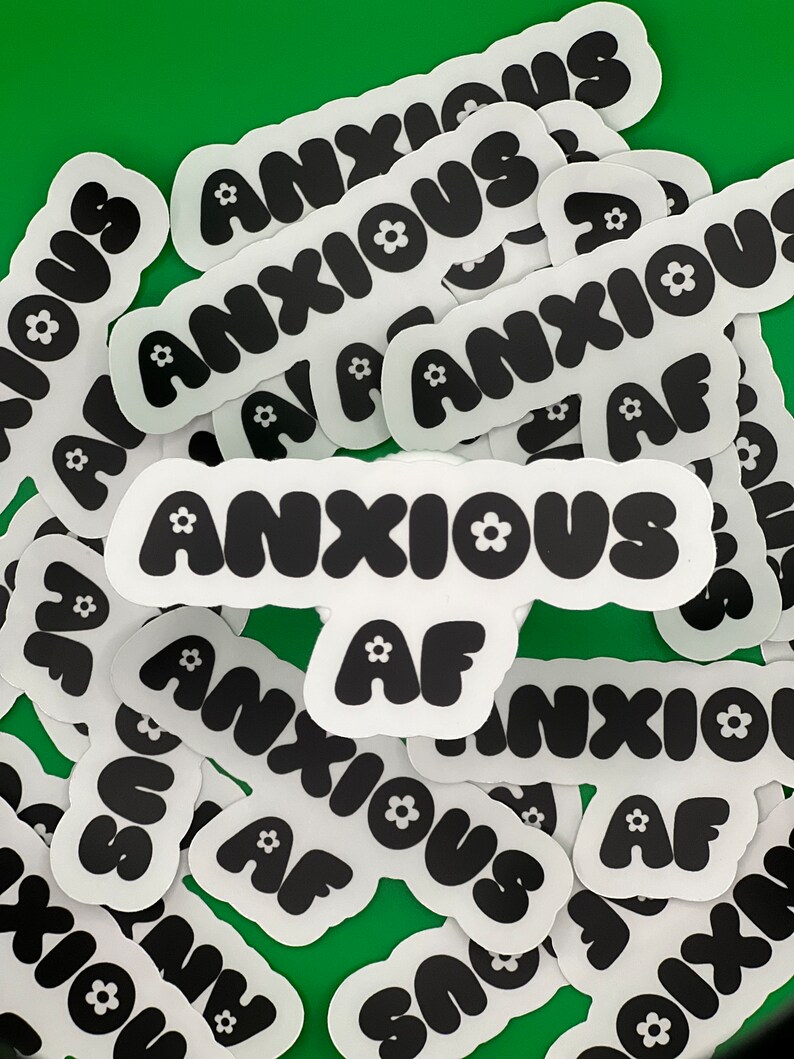 May include: A collection of white stickers with black text and a small flower design. The text on the stickers reads "Anxious AF".