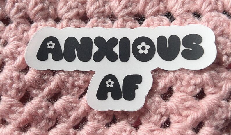 May include: A white sticker with black text that reads "ANXIOUS AF" in a bubble font. The letters have small white flowers on them.