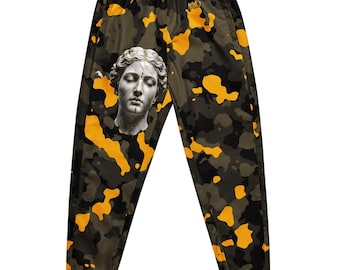 May include: Jogger trousers featuring a camouflage pattern in shades of olive green, black, and bright orange. The left leg displays a detailed graphic of a classical marble statue head with gold-coloured cracks. The text MUD is printed in gold.