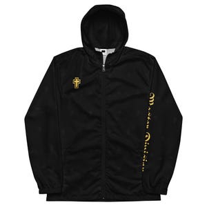 May include: A black zip-up hooded jacket featuring a gold cross emblem on the right chest and gold text running vertically down the left sleeve. The fabric has a subtle, repeating tonal cross pattern throughout the entire garment.