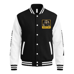 May include: A black and white varsity jacket featuring a graphic of a rhinoceros on the left chest with the text HEAVY IND. below it. The sleeves are white with black text reading HEAVY IND. and UNSTOPPABLE. It has a snap button front closure.