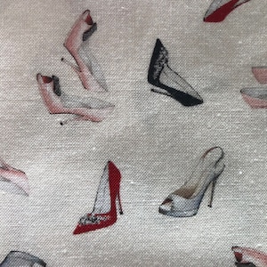 May include: A white fabric with a repeating pattern of various colored high-heeled shoes. The shoes are in shades of red, black, pink, and blue.