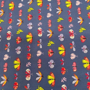 May include: A navy blue fabric with a repeating pattern of colorful butterflies and small floral accents. The butterflies are in shades of red, yellow, orange, and purple. The fabric is likely cotton or a similar material.