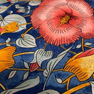 May include: A blue fabric with a floral pattern. The flowers are yellow, orange, and pink. The fabric has a vintage style.