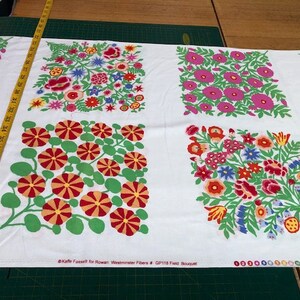 May include: White fabric with a repeating pattern of colourful floral bouquets. The fabric features four different designs, each with a unique arrangement of flowers. The fabric is labelled "GP118 Field Bouquet" and " Kaffe Fassett for Rowan, Westminster Fibers".