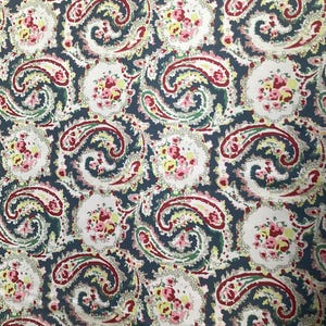 Könnte beinhalten: Paisley-Stoff mit einem sich wiederholenden Muster aus dunkelblauen, weißen, roten, rosa und gelben Blumen- und Wirbeldesigns. Der Stoff hat eine Vintage-Ästhetik, geeignet für Bekleidung oder Heimdekorationsprojekte.