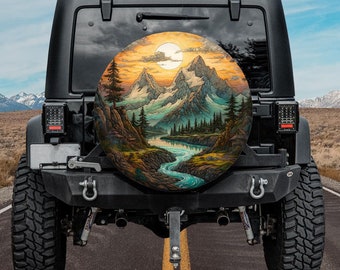 Pode incluir: Um Jeep preto com uma capa de pneu sobressalente com uma pintura de paisagem de montanhas, um rio e um pôr do sol. A obra de arte é circular e colorida, com tons de laranja, azul e verde. O Jeep está estacionado numa estrada pavimentada.