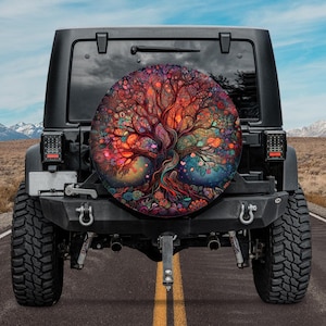 May include: A black Jeep with a colorful tree of life design on the spare tire cover. The Jeep is parked on a paved road with a mountain range in the background.