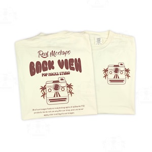 May include: Two cream-coloured t-shirts. One features a brown graphic of a vintage camera with palm trees and the text "Real Mockups BACK VIEW POP MOCKS STUDIO". The other shirt has the same camera graphic on the front. The shirts have a vintage aesthetic.
