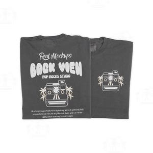 Puede incluir: Dos camisetas gris carbón. Una camiseta muestra el texto "Real Mockups BACK VIEW POP MOCKS STUDIO" con un gráfico de cámara. La otra camiseta tiene un gráfico de cámara más pequeño. El texto de la camiseta dice "All of our images feature real photographs of authentic POD products."