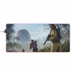 May include: A video game mouse mat depicting a post-apocalyptic scene with three figures in a woodland setting. One figure is wearing a yellow hazmat suit and a helmet, holding a rifle. The other two figures are wearing casual clothing and holding rifles. The background features a large, round structure in the distance.