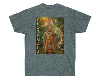 Puede incluir: Una camiseta gris con una imagen colorida de una persona con un tocado y ropa tradicional maya. El texto "GUATEMALA" está impreso verticalmente en el lado izquierdo de la imagen.