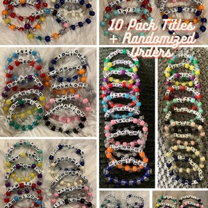 Pu&ograve; includere: Dieci braccialetti colorati con perline con diversi titoli di album della discografia di Taylor Swift. I braccialetti sono disposti in file su una superficie grigia. Il testo "10 Pack Titles + Randomized Orders" &egrave; stampato in nero su sfondo bianco.