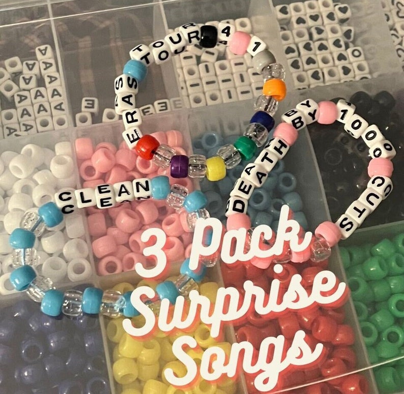 Pu&ograve; includere: Tre braccialetti colorati con perline con le parole "Clean", "Death By 1000 Cuts" e "Eras Tour" scritte. I braccialetti sono in un contenitore di plastica con altre perline.