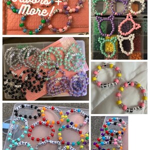 Pu&ograve; includere: Assortimento di braccialetti colorati con perline, con varie parole e frasi scritte, tra cui "Smile", "Big", "Dance", "123", "Good", "Hey", "Stop", "My", "Era", "Red", "Cardigan", "Wide", "Eyed", "Gay", "KC" e "Hella Good".