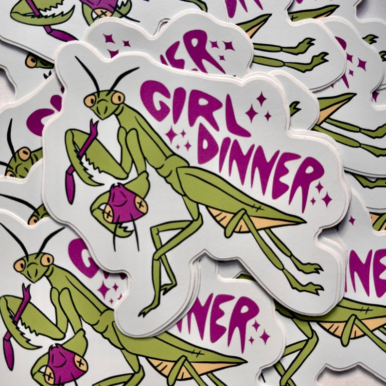 May include: A stack of stickers featuring a green praying mantis with a purple background. The text "Girl Dinner" is written in purple on the sticker.