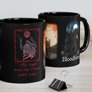 Puede incluir: Dos tazas de cerámica negra con temática del videojuego Bloodborne. Una taza presenta una ilustración roja y negra de una criatura con el texto "The Night and the Dream were long..." La otra taza presenta una ilustración roja y negra de un personaje en un bosque con el texto "Bloodborne".