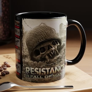 May include: Black ceramic mug featuring a graphic of a skull wearing a military helmet and the text "Resistance Fall of Man".