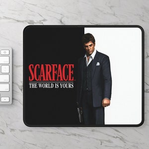 May include: Black and white mousepad with a red "Scarface" logo and the text "The World Is Yours". A man in a suit is standing on the right side of the mousepad.