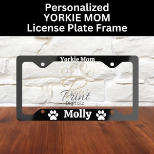 May include: Black metal license plate frame with the text "Yorkie Mom" and "Molly" with paw prints on either side.