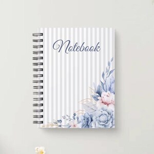May include: A spiral-bound notebook with a cover featuring vertical gray and white stripes. The word "Notebook" is written in cursive. The lower right corner is decorated with watercolor flowers in shades of blue and pink.
