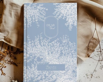 May include: A light blue journal with a white floral design and the text "Dear God" in a circle. The bottom of the cover reads "Prayers from Winnie Chan".