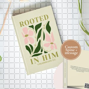 May include: A cream-coloured journal with a floral design and the text "Rooted in Him Colossians 2:7". The journal has a custom spine and message.