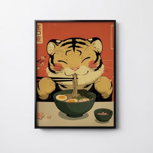 Könnte beinhalten: Gerahmter Kunstdruck mit einem Zeichentricktiger, der Ramen genießt. Der Tiger wird mit einem glücklichen Gesichtsausdruck dargestellt, der Nudeln aus einer grünen Schüssel isst. Der Hintergrund ist rot mit japanischem Text.