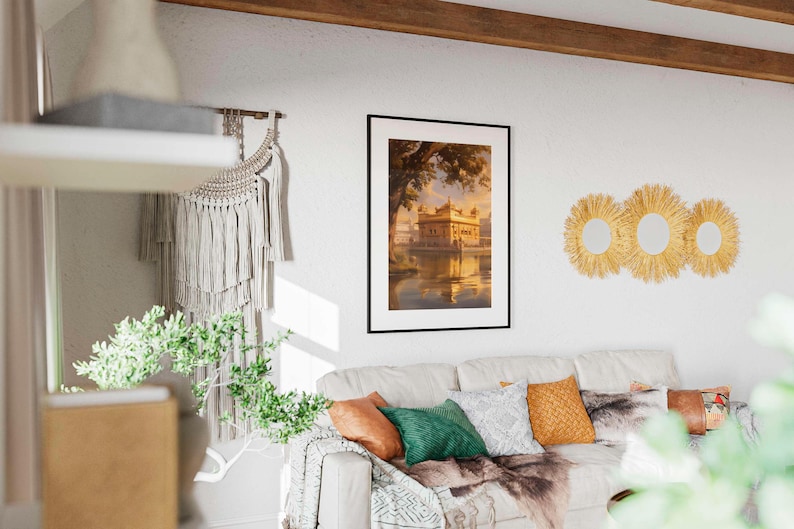 May include: A framed print of a golden building with a reflection in the water. The print is hanging on a white wall with a macrame wall hanging and three woven straw sunburst mirrors.