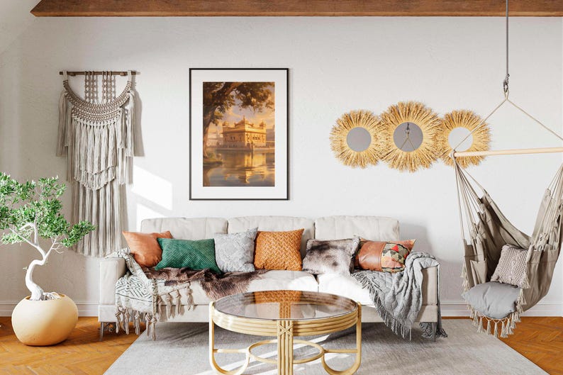 May include: A living room interior with a white couch, a wooden coffee table, a hanging hammock, and a framed print of a golden building reflected in water. The room is decorated with a macrame wall hanging, three woven sunburst mirrors, and a potted plant.