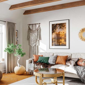 May include: A white couch with a variety of throw pillows in a living room with a wooden ceiling, a large window with beige curtains, a potted plant, a coffee table with a glass top, and a wall hanging.