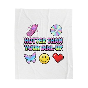 May include: White blanket with a colourful design featuring a flip phone, CD, butterfly, smiley face, and pixelated heart. The text "HOTTER THAN YOUR DIAL-UP" is in the centre.