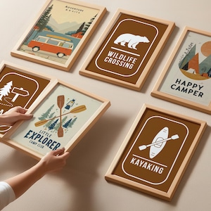 Puede incluir: Una colecci&oacute;n de l&aacute;minas enmarcadas con tem&aacute;tica de camping. Las l&aacute;minas presentan ilustraciones de una furgoneta camper, un oso, monta&ntilde;as y equipo de camping. La paleta de colores incluye marr&oacute;n, beige, naranja y azul. El texto incluye "Adventure Awaits", "Wildlife Crossing", "Happy Camper", "Little Explorer Camp Club", "Kayaking".