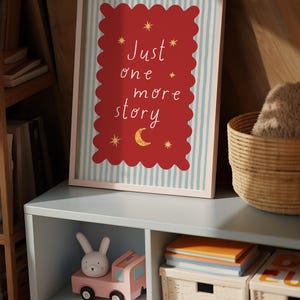 a framed poster with the text "Just one more story" on it, placed on a shelf next to a toy car and a basket.