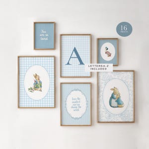 Puede incluir: Una colección de láminas artísticas enmarcadas en tonos azul claro y dorado. Las láminas incluyen ilustraciones de conejos, patos y citas inspiradoras. El conjunto incluye 16 láminas y las letras A-Z.