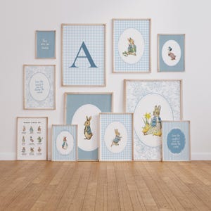May include: A collection of framed art prints featuring illustrations of rabbits, ducks, and floral patterns in shades of blue and white. Some prints include text, and the frames are light wood.