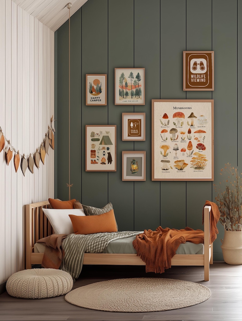 Puede incluir: Una acogedora escena de dormitorio con una cama de madera, almohadas y una manta color &oacute;xido. La pared presenta impresiones art&iacute;sticas enmarcadas con temas de acampada y setas, incluyendo textos como "Happy Camper" y "Wildlife Viewing". Una alfombra tejida y un puf completan el espacio.