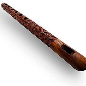 Puede incluir: Una flauta de madera hecha a mano con intrincadas tallas florales. El instrumento es de un color marrón oscuro intenso y presenta múltiples orificios para los dedos y un orificio de sonido rectangular. La superficie de la flauta es lisa, con tallas en relieve detalladas.
