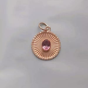 Peut inclure: Un pendentif en or rose avec une pierre ovale rose sertie dans un motif soleil avec un halo de diamants.