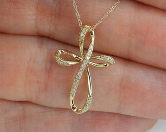 May include: A gold chain necklace with a diamond-encrusted cross pendant. The cross is a delicate, twisted design.
