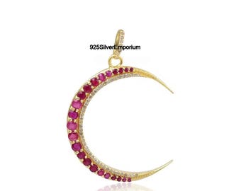 May include: A gold crescent moon pendant featuring a row of round, vibrant pink rubies along the outer edge and a thinner row of small, clear white stones along the inner curve. The pendant includes a small bail at the top and the text 925SilverEmporium.