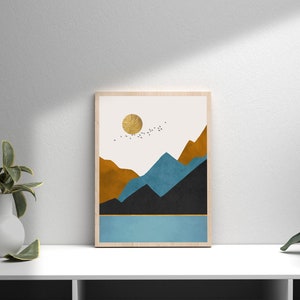 May include: A framed art print featuring a minimalist landscape. The artwork depicts a gold sun, mountains in shades of brown, blue, and black, and a blue lake. A flock of birds flies across the sky. The frame is made of light wood.