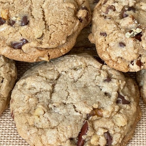 May include: Close-up of several chocolate chip cookies with pecans. The cookies are golden brown and have a slightly crispy texture.