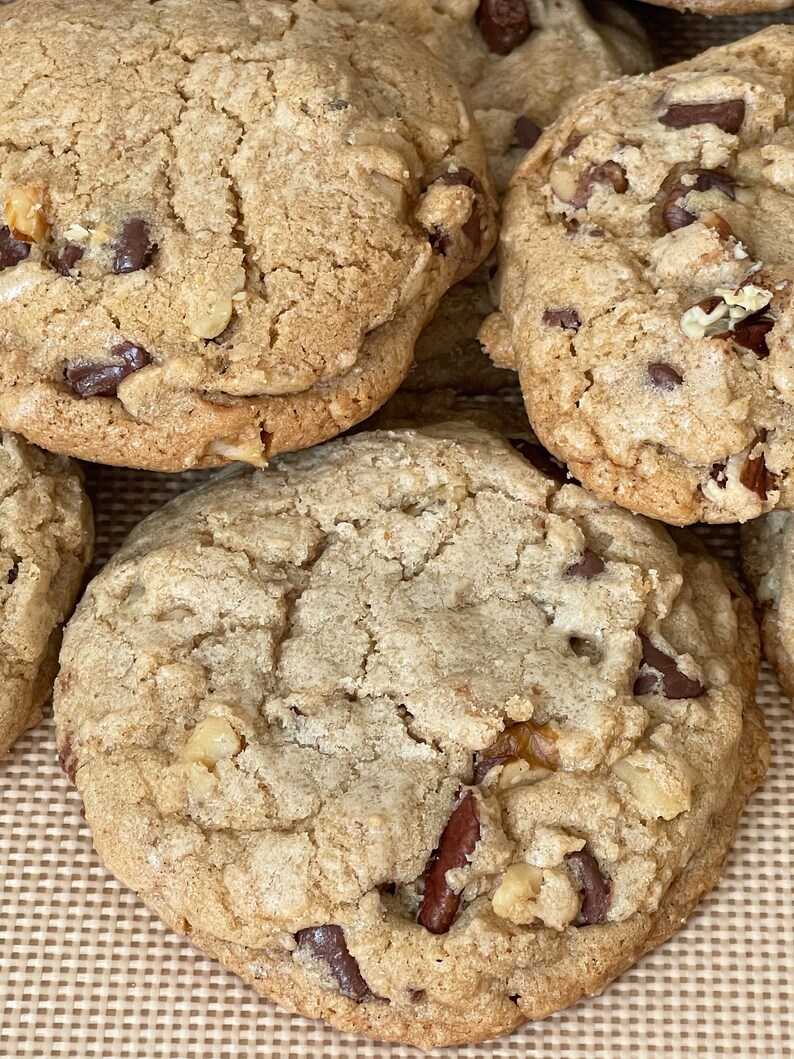 May include: Close-up of several chocolate chip cookies with pecans. The cookies are golden brown and have a slightly crispy texture.