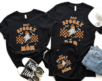 May include: A set of three black t-shirts with a ghost skateboarding graphic and the text "One Spooky Mom", "One Spooky Dad", and "One Spooky Dude".