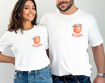 Op de afbeelding: Een stel draagt witte T-shirts met perzikillustraties en de woorden "Mama" en "Dada" erop.